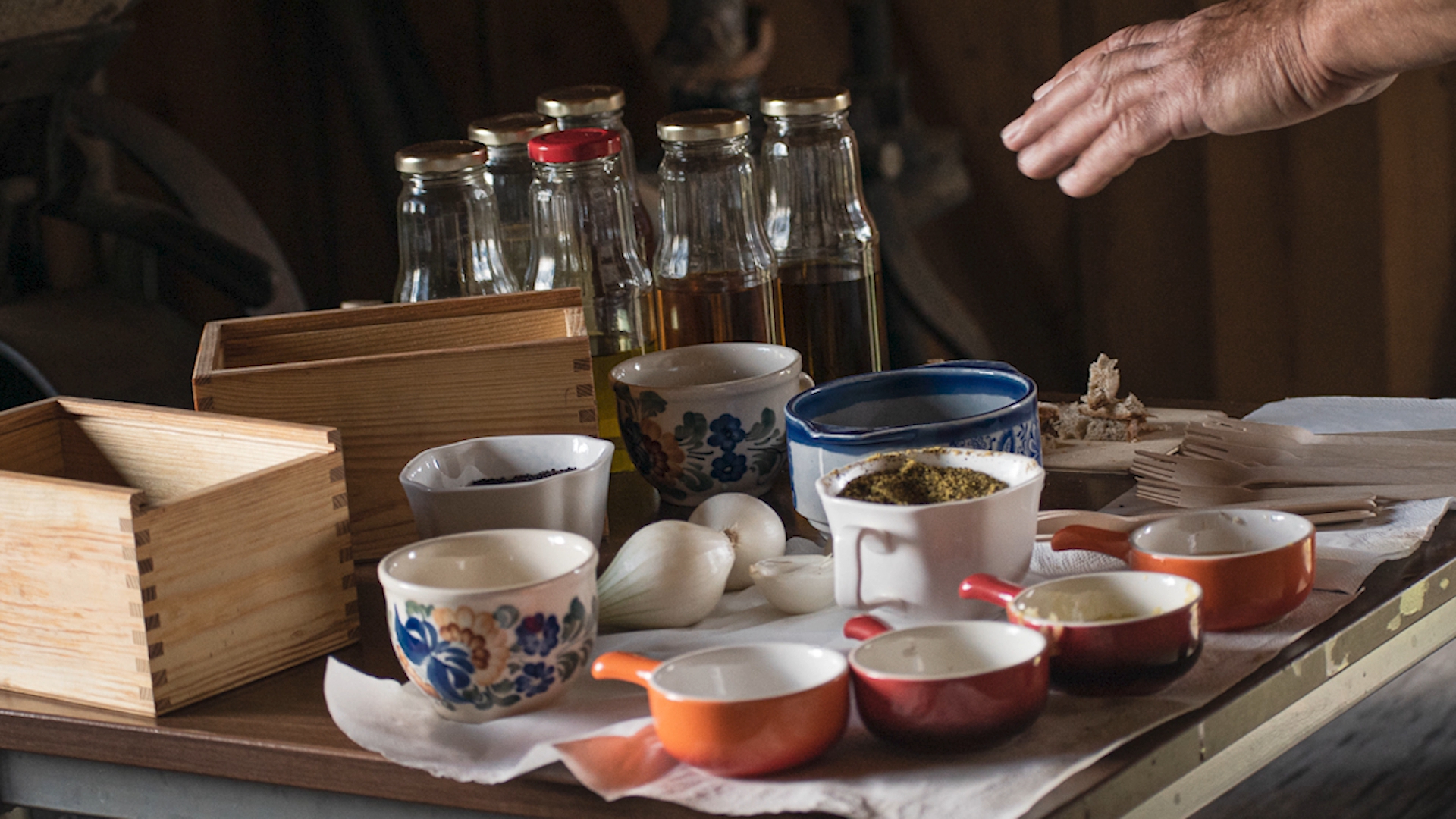 zdjecie przedtsawiające stół, na którym znajdują się szklane butelki z olejem oraz różne przyprawy