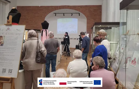 prowadząca wykład omawiająca jakieś zagadnienie przy wyświetlanej z rzutnika na ścianie prezentacji