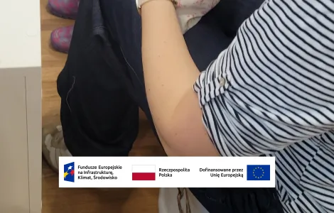 dłonie obwiązujące materiałową kulkę włóczką (prawdopodobnie główkę lalki - motanki)