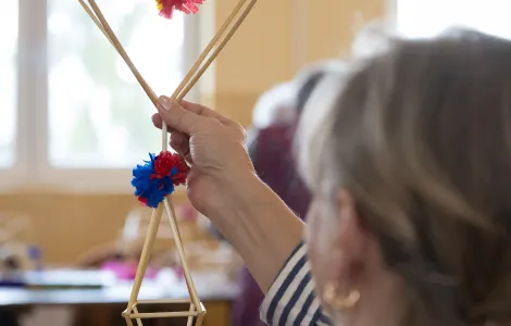 na zdjęciu kobieta trzymająca powstającego słomkowego pająka