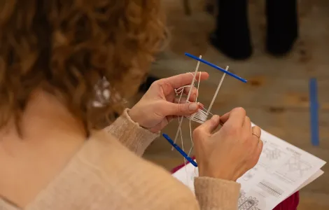 kobieta trzymająca widełki do tworzenia chusty kamelowej i odtwarzająca wzór