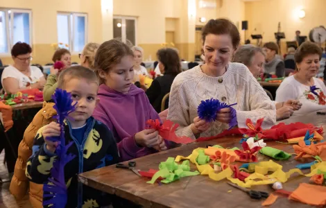 uczestnicy warsztatów tworzący kwiaty z bibuły 